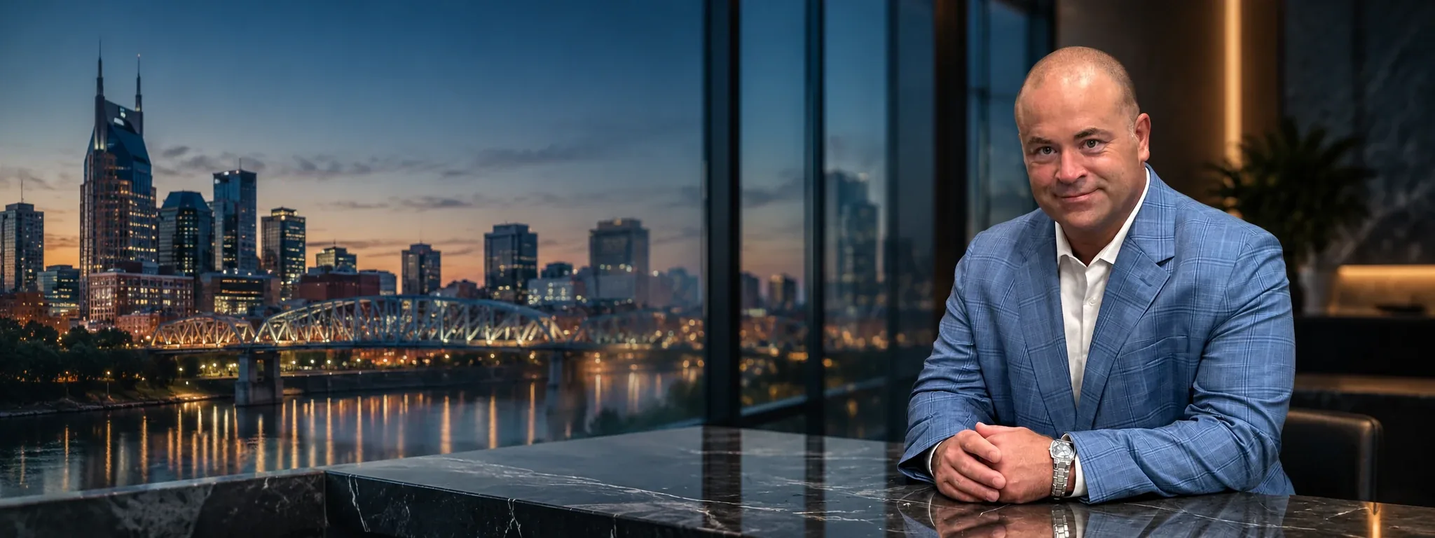 Carson Jones, founder of Passive Investments, at a marble desk with the Nashville skyline at dusk